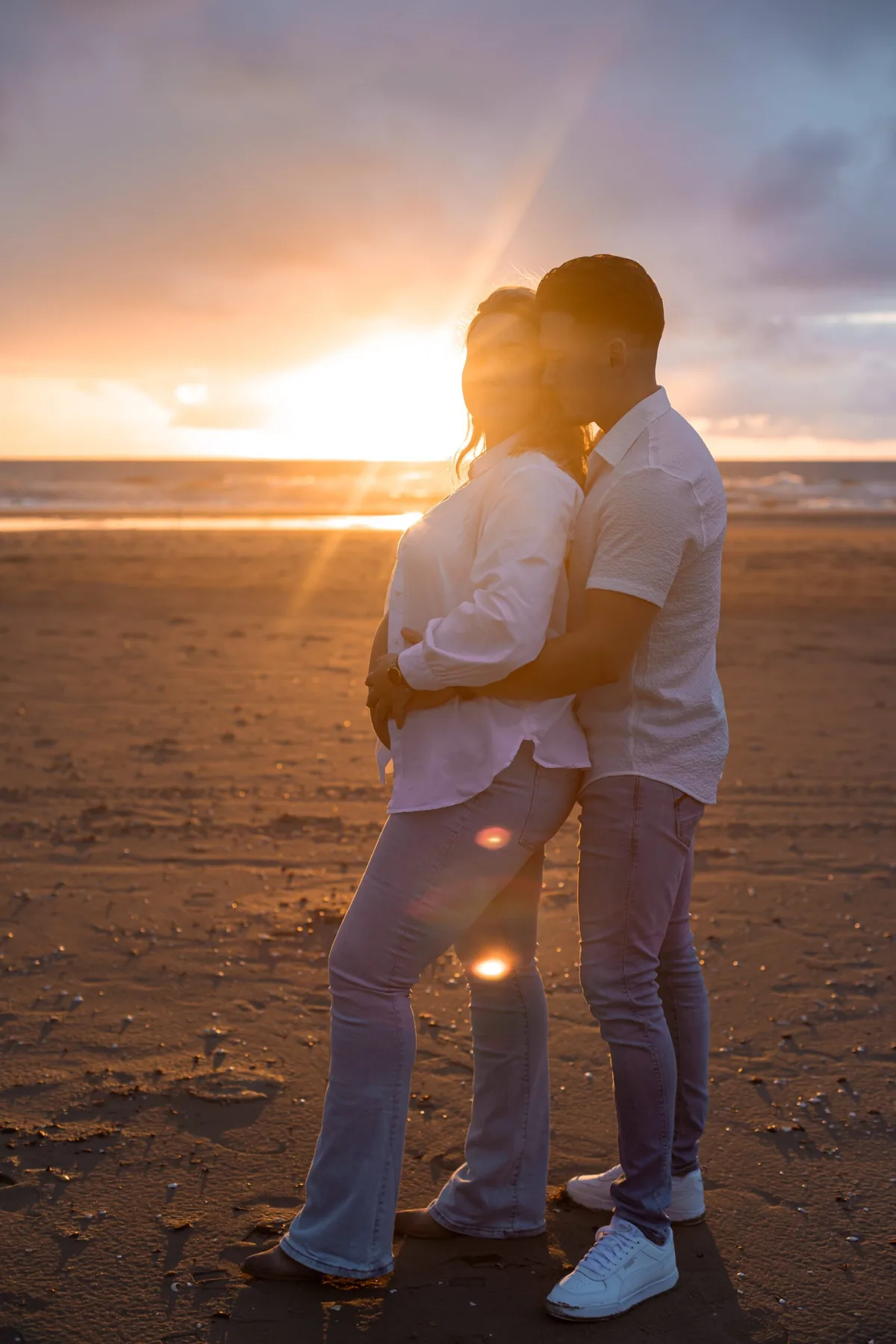 Zwanger stel op het strand bij zonsondergang